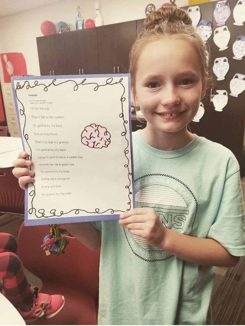 Charleigh smiling while holding a copy of her poem.